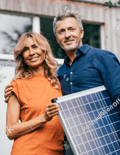 Couple holding a solar panel outside their home